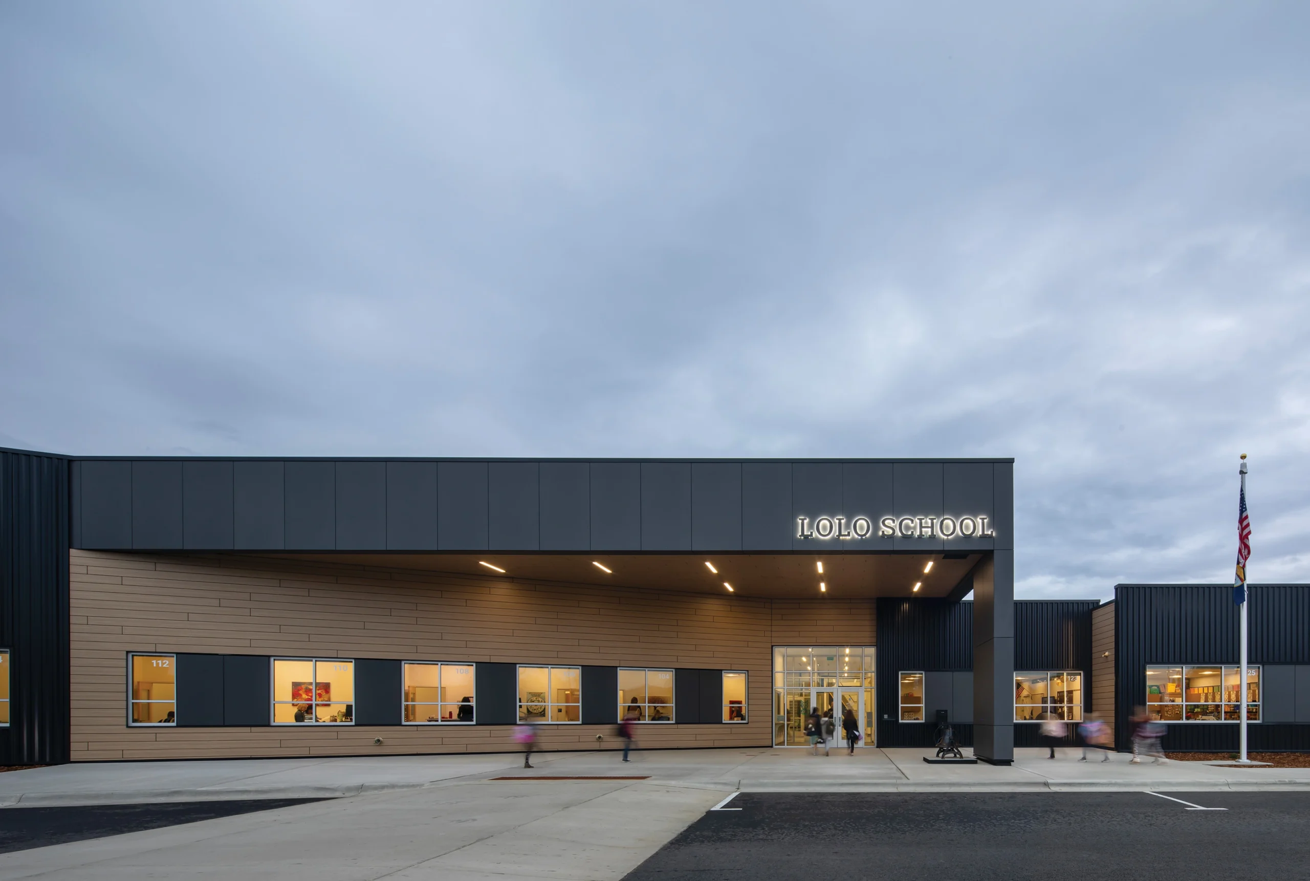 The modern exterior of Lolo K-8 School features a cohesive architectural design with clean lines, expansive windows, and a welcoming entrance, reflecting the school’s transformation into a unified, innovative educational campus for the community.