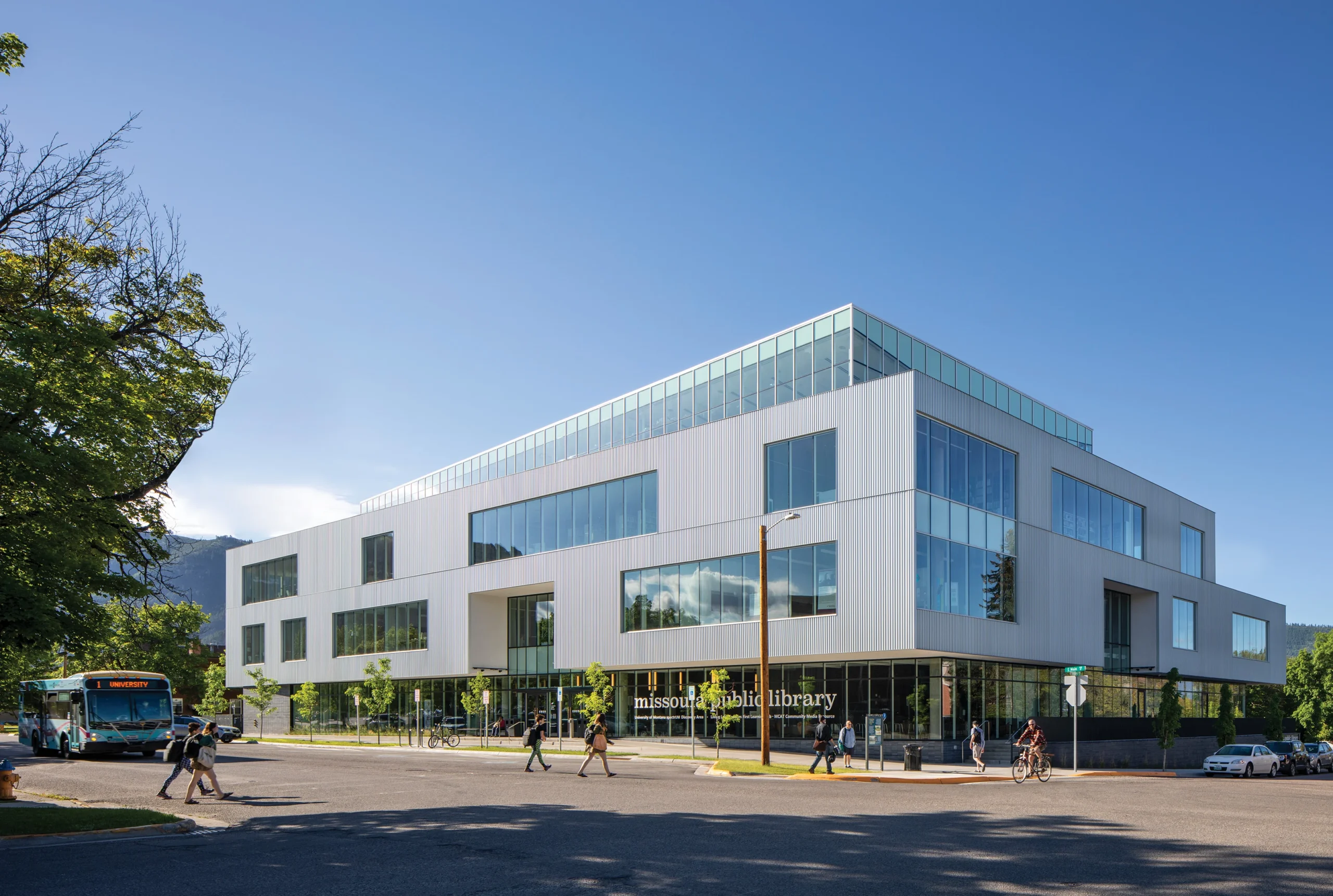 Exterior of Missoula Public Library, featuring a modern design with expansive glass windows, metal paneling, and a cantilevered entrance.