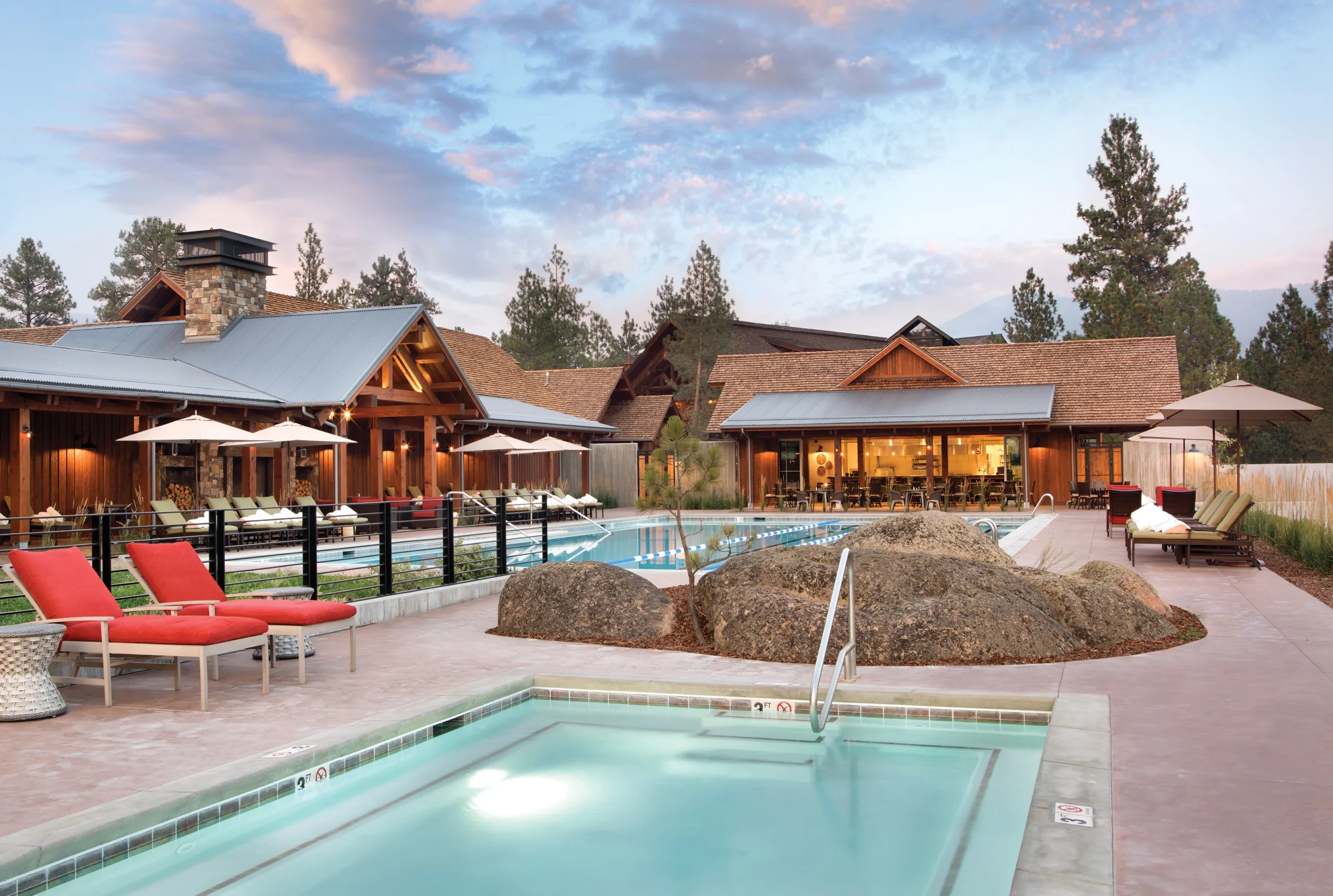 Outdoor pool and spa area at Stock Farm Club featuring natural stone accents, modern lounge seating, and rustic wooden architecture, blending luxury with the surrounding Montana landscape.