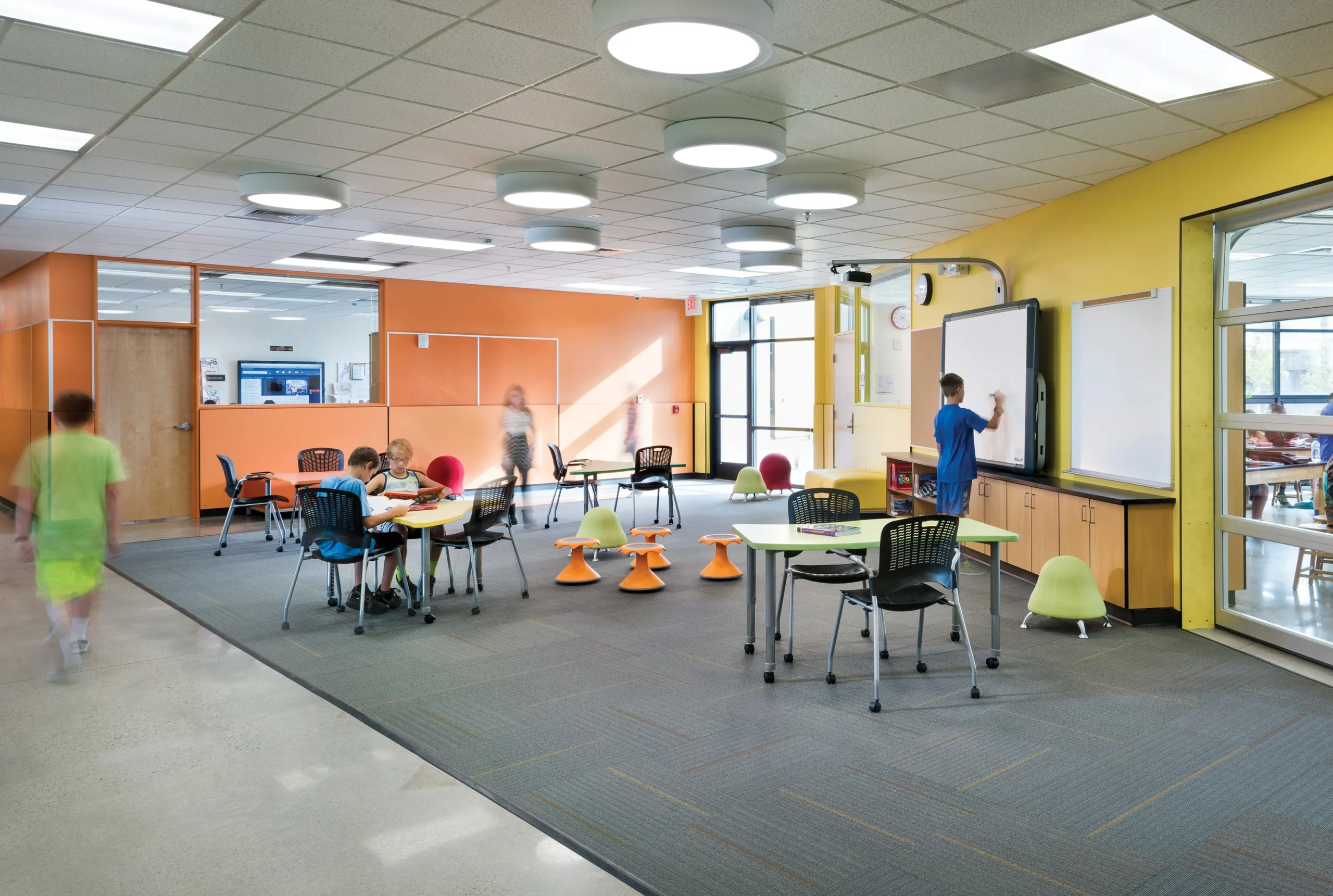 A flexible learning space at Elysian K-8 School features colorful walls, mobile furniture, writable whiteboards, and adaptable seating arrangements that encourage interactive and collaborative learning experiences.