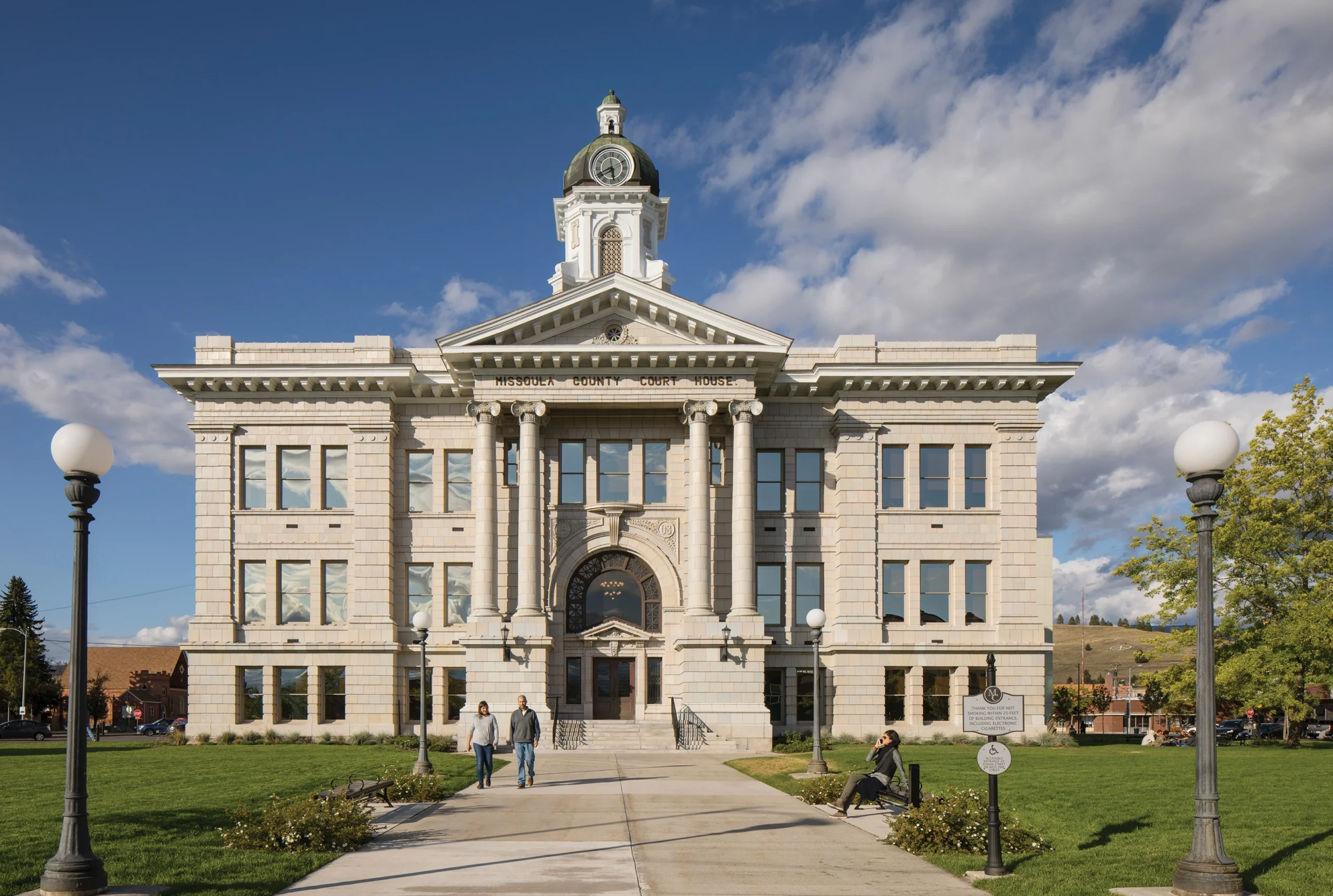 Restored exterior of the Missoula County Courthouse, a neoclassical sandstone building featuring grand columns, an ironclad cupola, and clock tower with a two-ton bell.