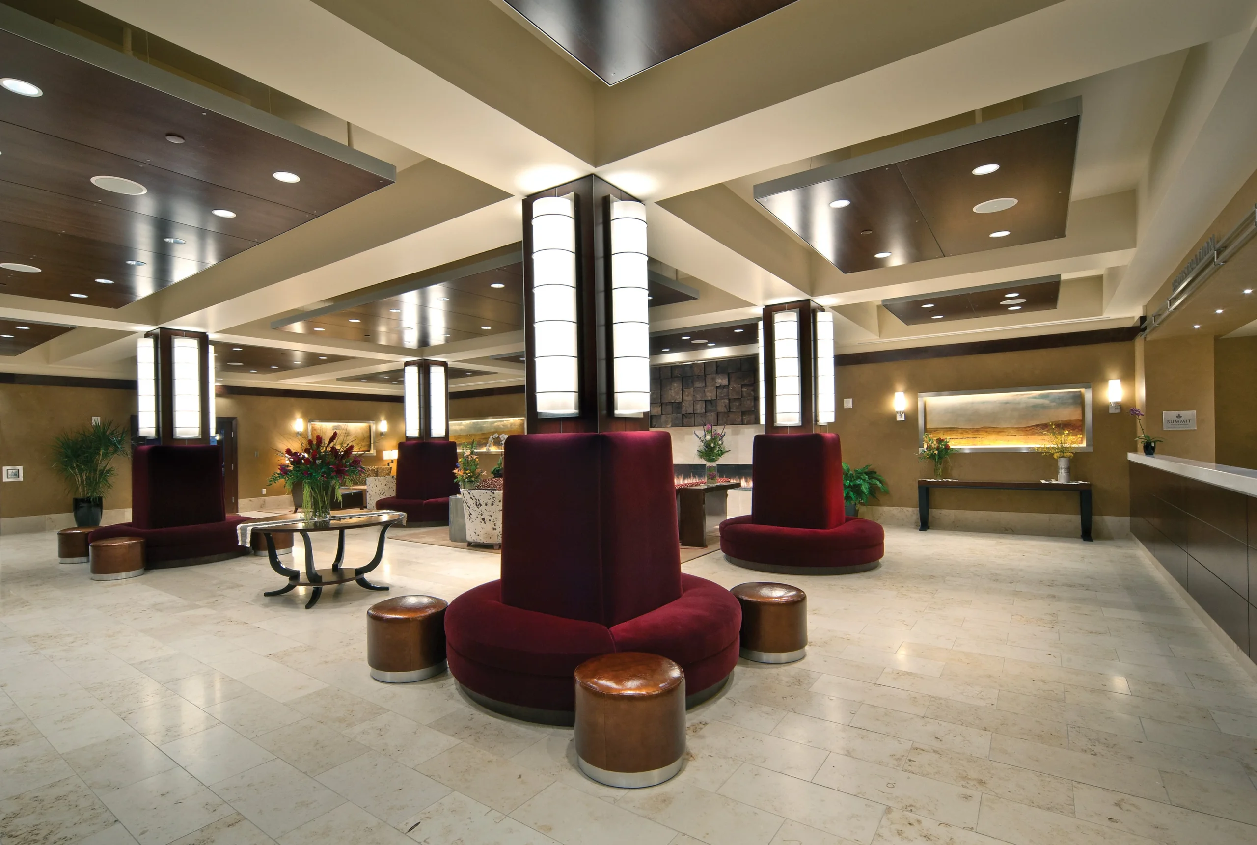 Contemporary lobby at the Northern Hotel featuring bold burgundy seating around illuminated columns, modern ceiling design, and elegant accent lighting, creating a welcoming and sophisticated guest experience.